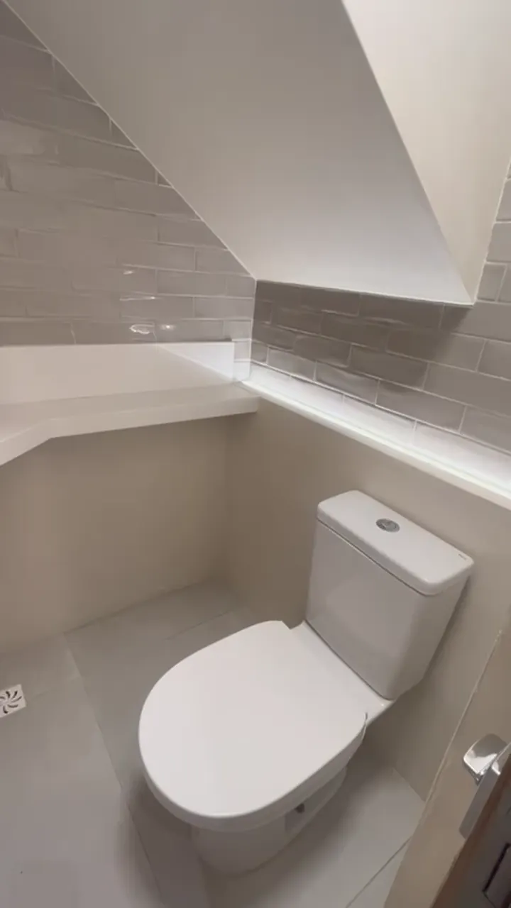 Lavabo sob a escada com bacia e revestimento claro