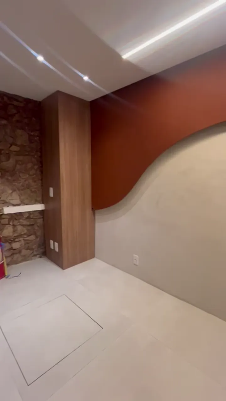 Parede curva em tom terracota com luz embutida na sanca