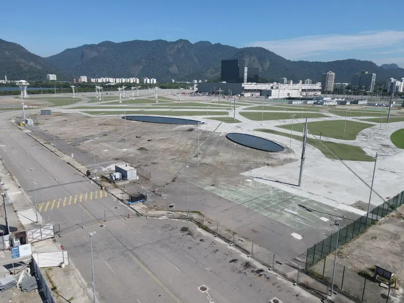 Praça ampla de piso cinza e sem uso, vista do alto