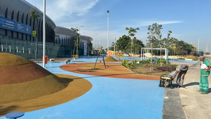 Área de lazer com piso azul, montes de areia e equipe finalizando