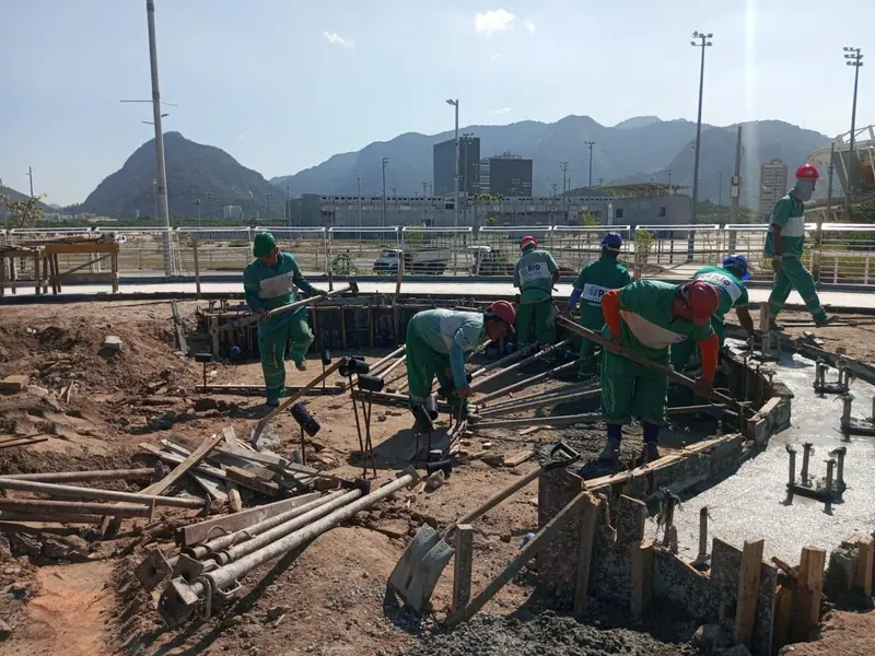 Equipe trabalhando em fundação com serra ao fundo
