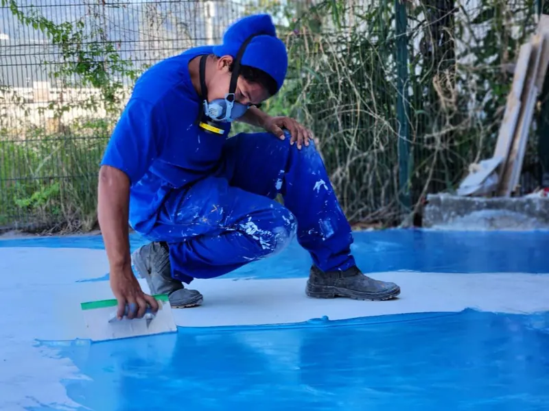 Pintor aplicando tinta azul no piso